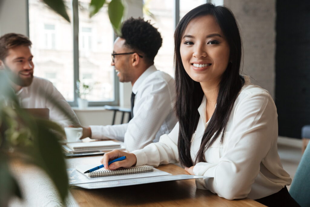Cheerful young asian businesswoman near colleagues