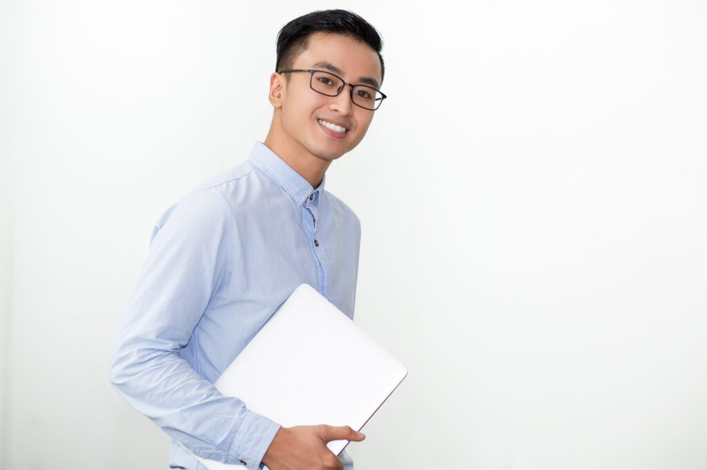 Smiling student in glasses carrying laptop