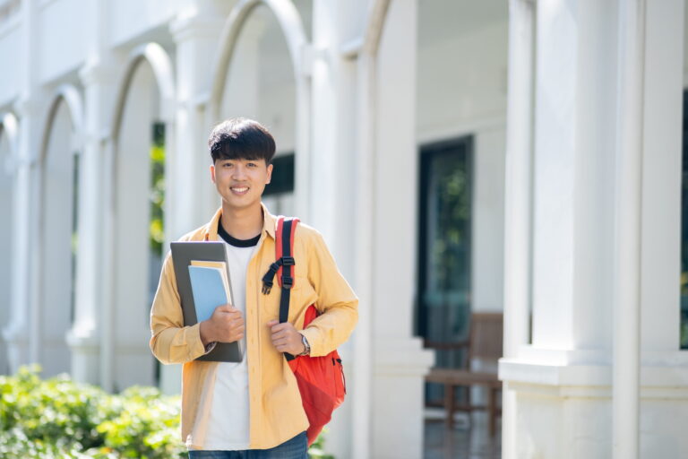a college student carrying a laptop and books