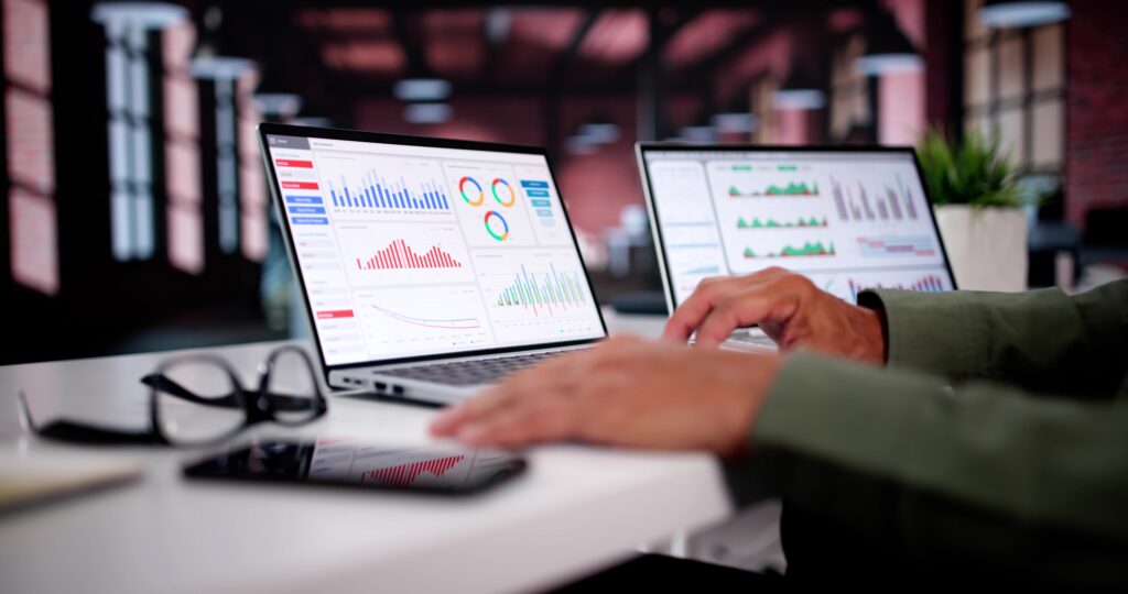an accountant looking at two different monitors with different data graphs