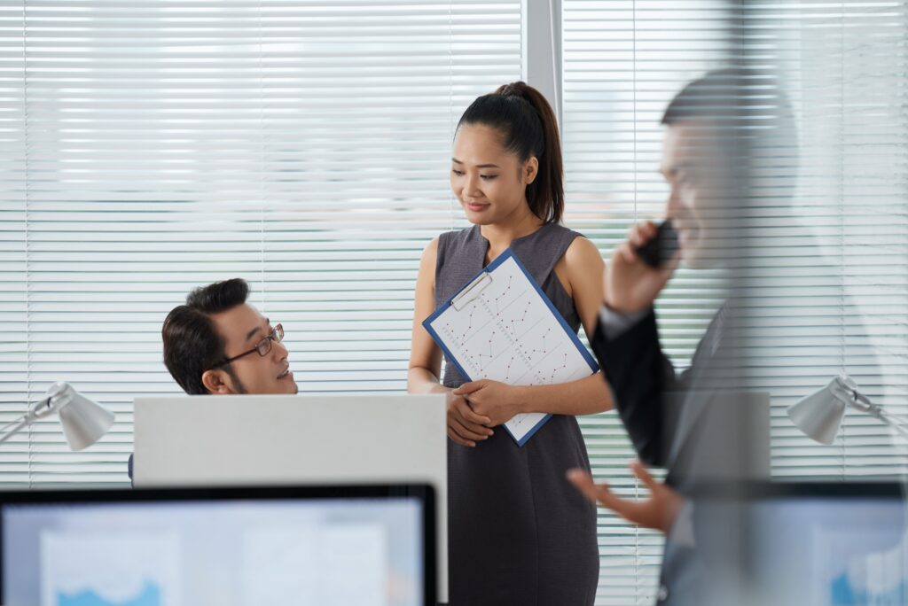 Coworkers discussing something while their colleague is talking on phone
