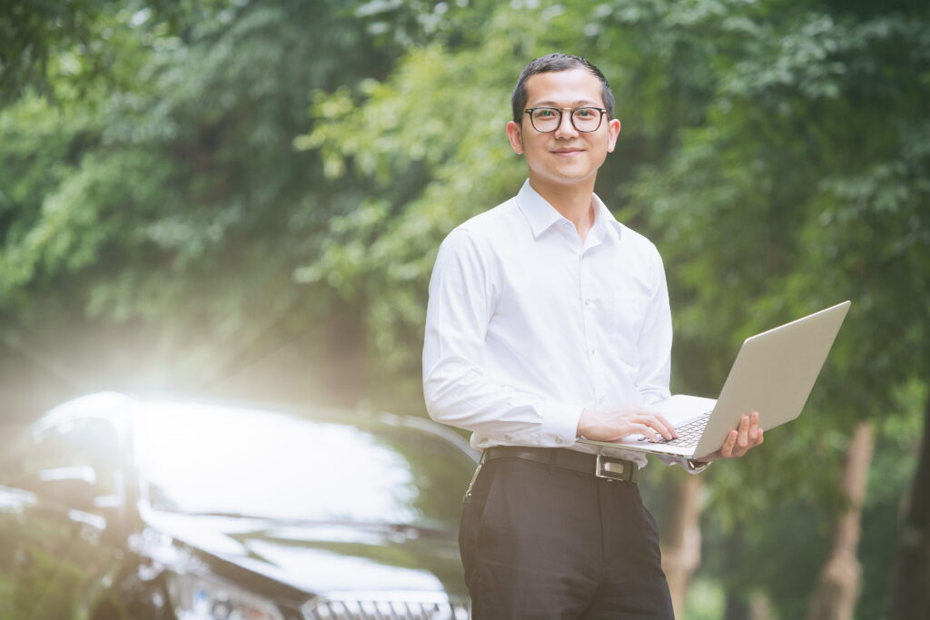 Businessman working with a laptop on the side of the car