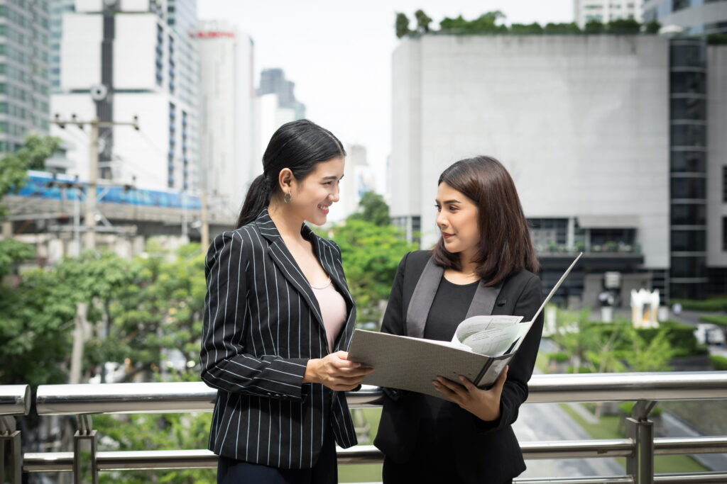 Businesswomen discussing over paperwork together outside