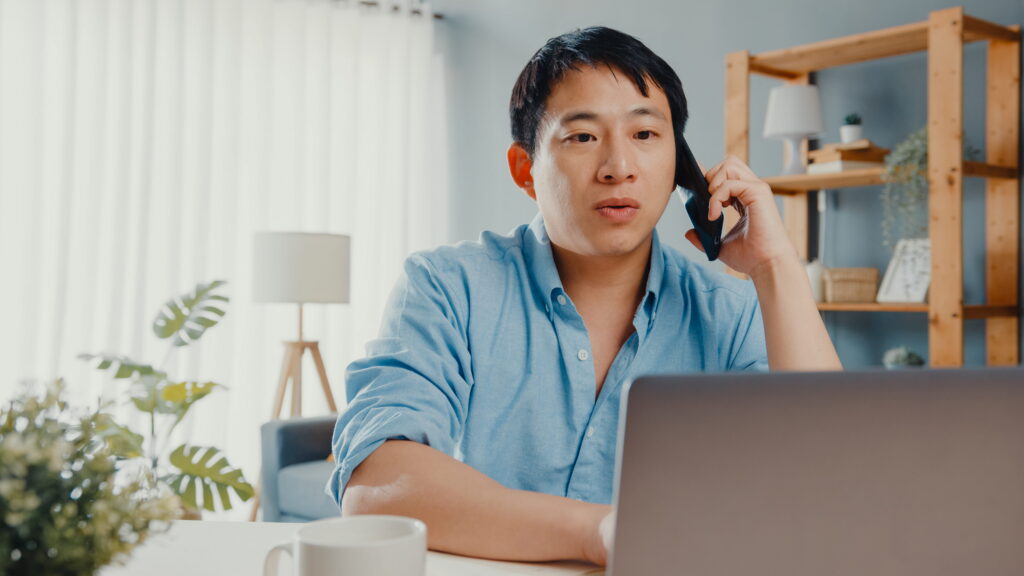 Freelancer using laptop and cellphone in living room at house