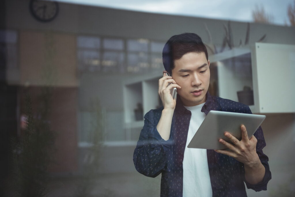 Property manager talking on mobile phone while using digital tablet.