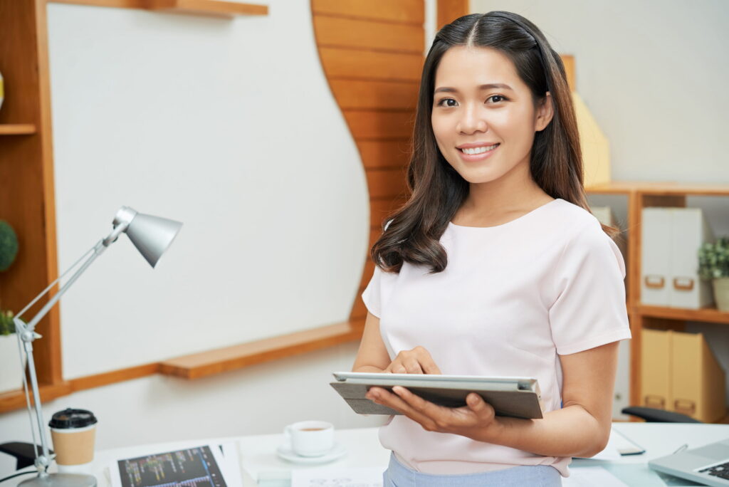Contemporary businesswoman with tablet smiling at camera.