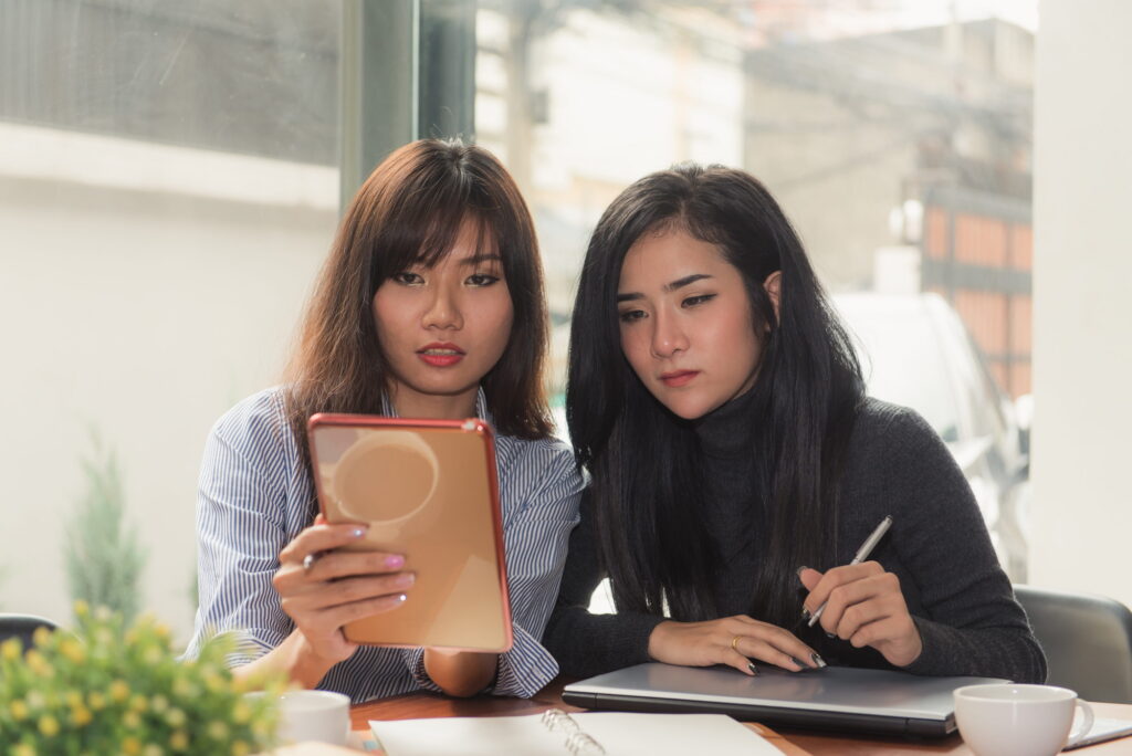 Two young business women sitting at table in cafe